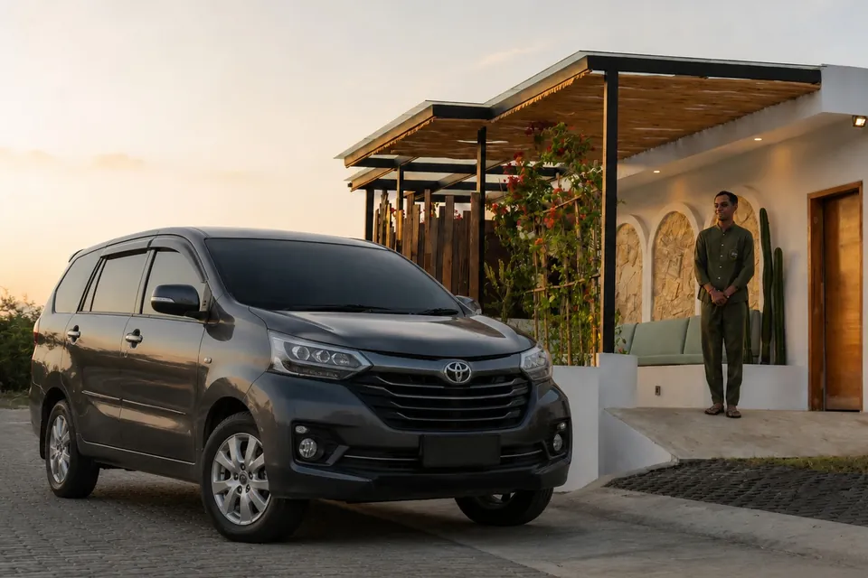 A dark grey Toyota Avanza parked at the villa entrance at sunset, with the driver waiting by the door