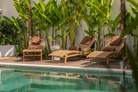 Les transats au bord de la piscine de Villa Soluna, entourés de végétation